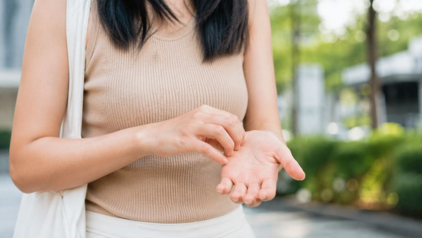 Женщина чешет левую руку