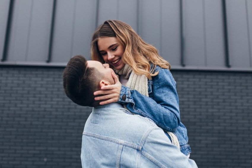 Хлопець каже дівчині комплімент піднявши її на руках Хлопець каже дівчині комплімент піднявши її на руках