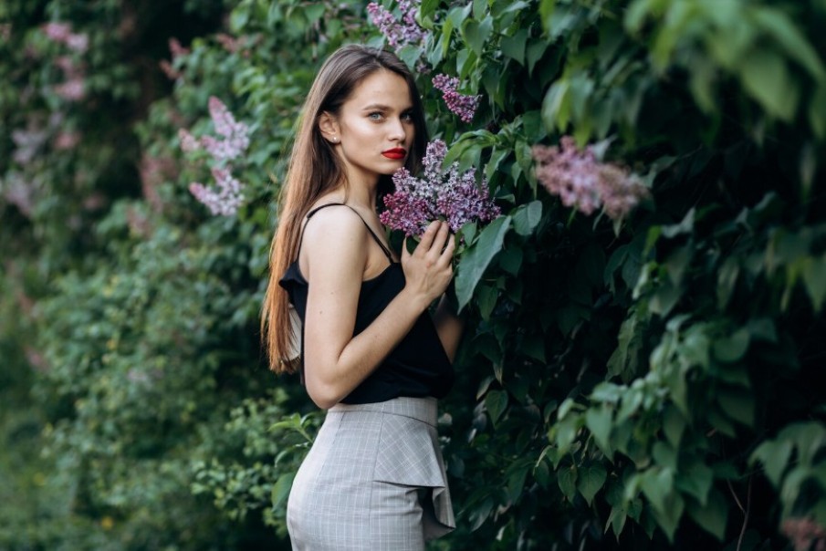 Чарівна дівчина стоїть біля куща бузку