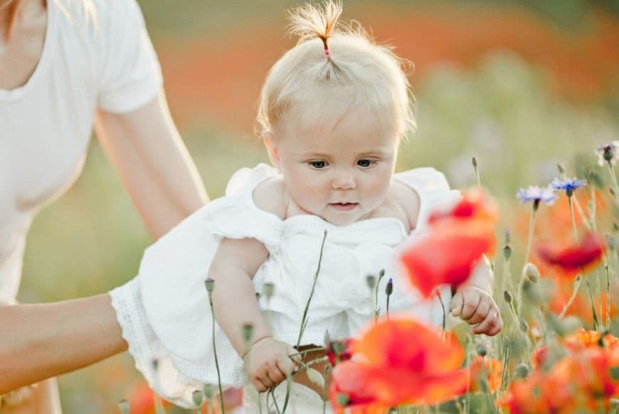 Маленька дівчинка дивиться на польові квіти | Сучасні імена для дівчаток 2026 Маленька дівчинка дивиться на польові квіти | Сучасні імена для дівчаток 2026